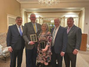 Three people posing with two award recipients at an awards ceremony.