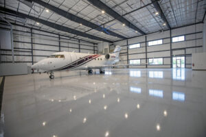 A private jet sits parked inside a sleek, modern airplane hangar.