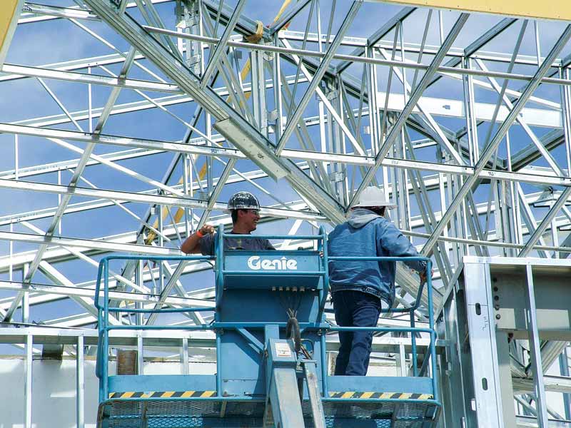 Construction workers look over a project with light-gauge steel framing. 