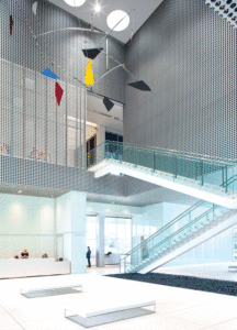 Photo © Richard Barnes/Courtesy Accurate Perforating and Linetec Perforated metal screens in the Tampa Art Museum, with a piece of art hanging overhead and a staircase to the right.