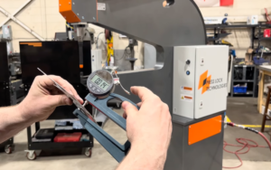 A photo of a worker checking gauges on the clinching machine. 