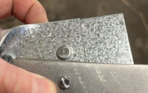 A close of a piece of metal that has experienced issues in the clinching machine. 