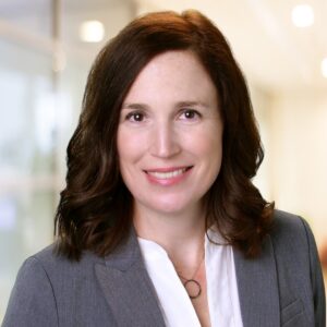 a woman with brown hair wearing a grey suit