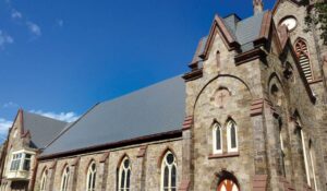 The stone church building with a metal roof. 