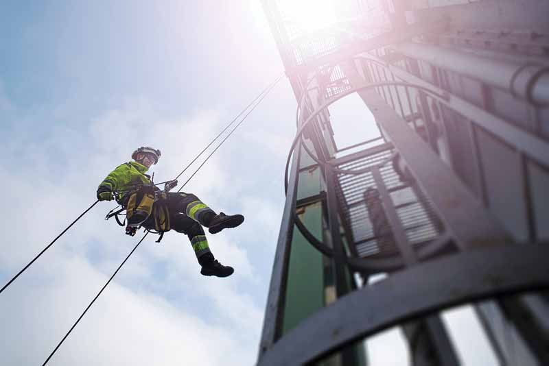 PHOTO BY CHARLIECHESVICK/©GETTY IMAGES A worker positions him down the side of the building on a safety line.