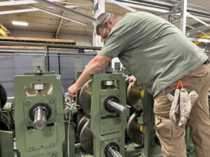 A worker performs maintenance on rollforming equipment. 