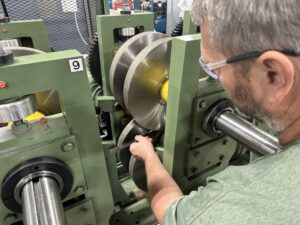 A worker performs maintenance on rollforming equipment. 