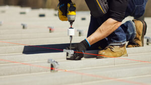 Courtesy AceClamp A worker drills screws into a roof clamp.