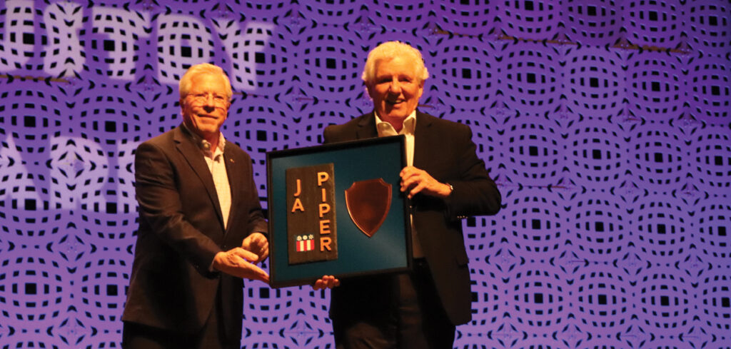Bob Daly standing with Dennis Conway and handing him a plaque