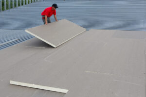 Courtesy Elevate Commercial Roofing Systems A worker putting insulation over a metal roof, both used in data centers.
