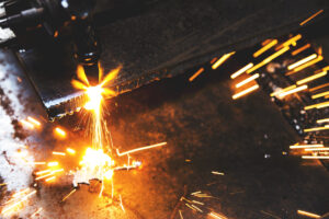 Plasma cutter in work, on the ground in hazardous conditions, one of the services offered by Andrews Fabricators. 