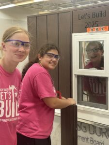 Three young girls pose for a photo while working during a summer camp hosted by ATAS International. 