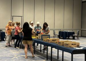 Photo courtesy Fenestration and Glazing Industry Association FGIA Fall Conference attendees stand at a table filling backpacks for underprivileged children.