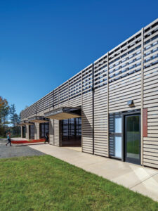 A couple carries a canoe into a building with bifold doors. 