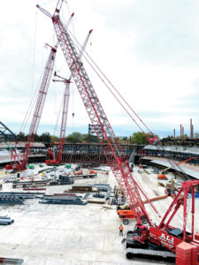 A group of large cranes on a metal construction job site. 