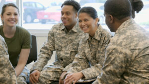 Photo (c) SDI Productions/Getty Images A mid adult female military officer wears camouflage as she sits among a group of new recruits in a training classroom. She holds a clipboard.