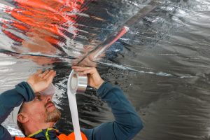 The construction worker used aluminum tape and had a roller for vapor barrier joints on the roof.