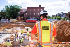 A worker wearing a vest with the Coakley & Williams Construction logo. 