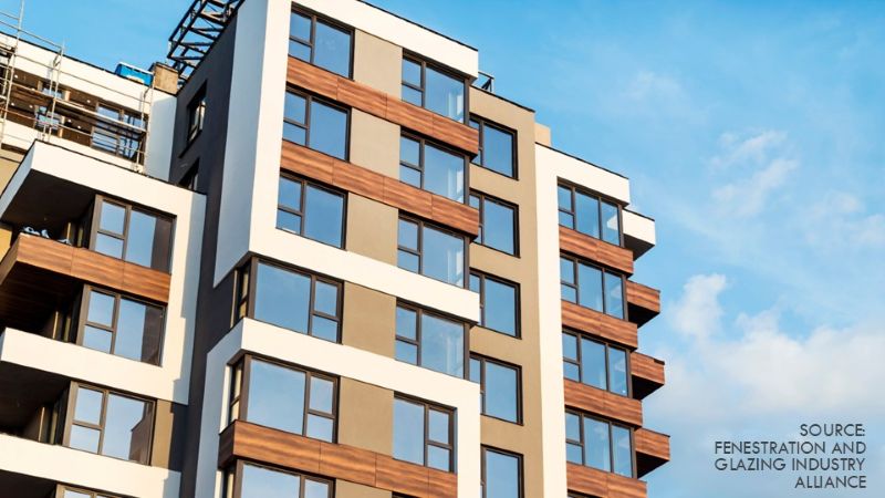 Photo shows modern multi-story residential building with large windows and mixed facade materials, illustrating typical fenestration systems.