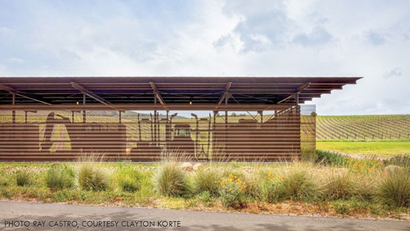 Exterior view of the Alma Rosa Vineyard barn with perforated corrugated metal cladding and vineyard rows extending across the surrounding landscape.