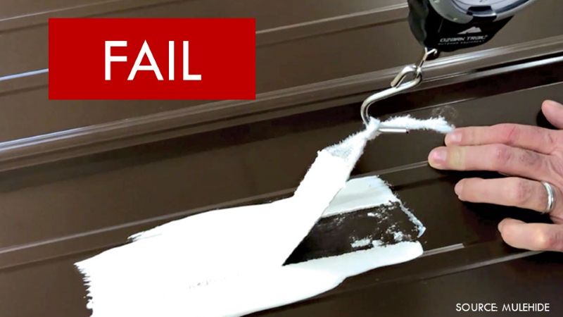 Strip of white roof coating peeling completely away from a brown metal roof panel during an adhesion test.